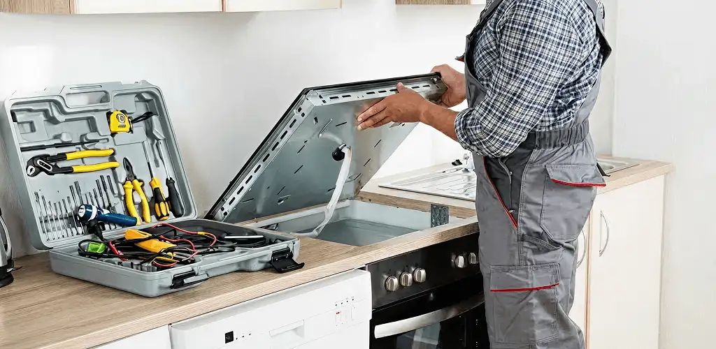 Handyman repairing a cooktop and checking wiring connections in Bakersfield, CA