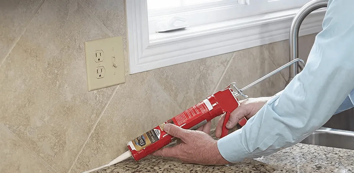 Handyman applying caulk along a kitchen backsplash and countertop seam in Bakersfield, CA