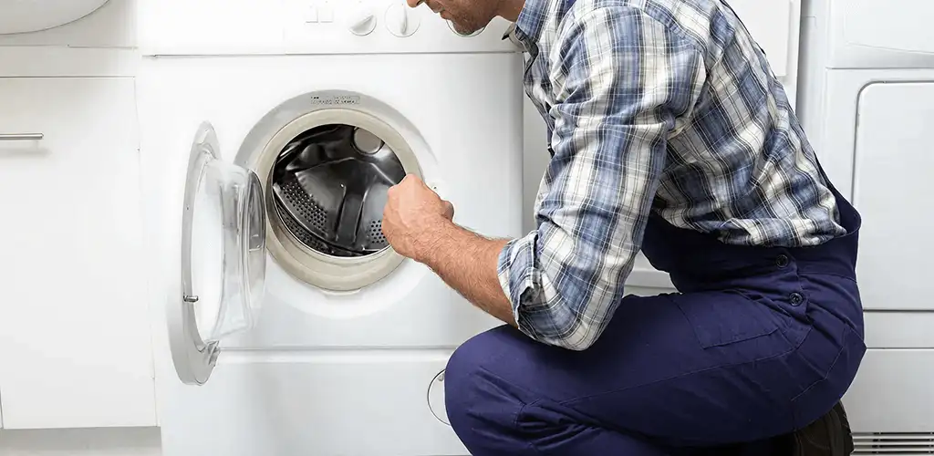 Handyman inspecting a dryer drum and internal parts for repair in Bakersfield, CA