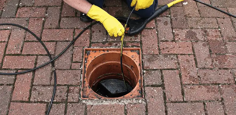 Drain cleaning technician using a drain snake to clear a clogged drain in Bakersfield, CA