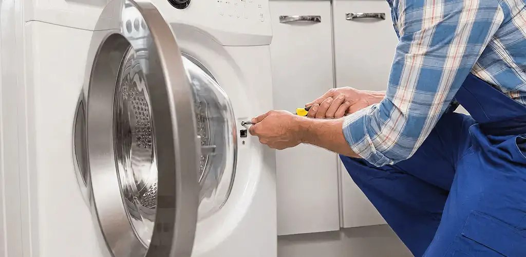 Handyman repairing a clothes dryer and checking electrical connections in Bakersfield, CA