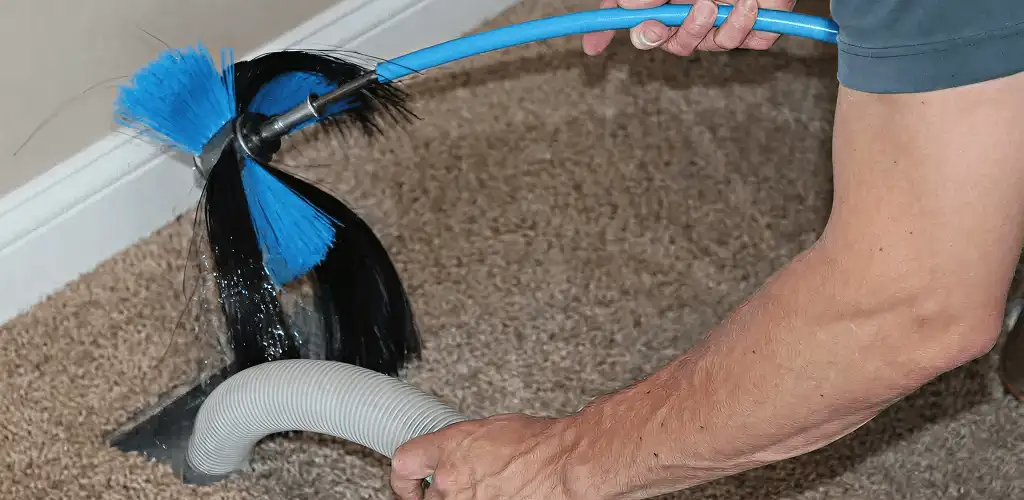 Dryer vent cleaning technician brushing lint from a vent line in Bakersfield, CA