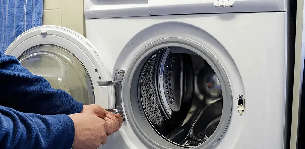 Washing machine repair handyman checking a front-load washer door and latch in Bakersfield, CA