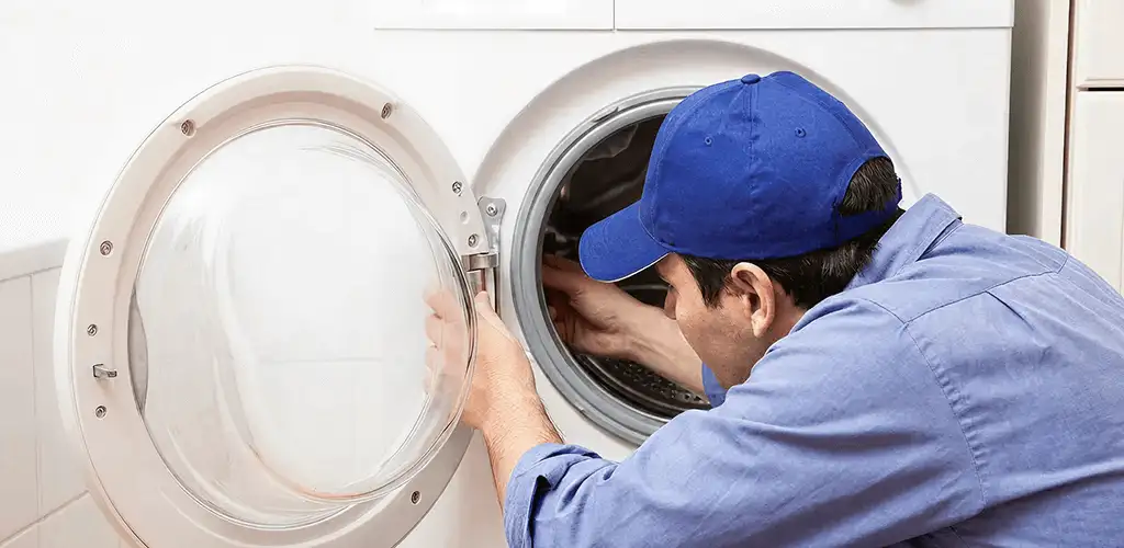 Washing machine repair handyman inspecting a front-load washer drum in Bakersfield, CA