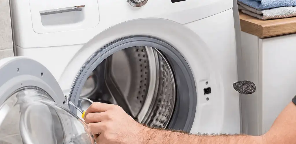 Handyman repairing a front-load washing machine and inspecting the drum in Bakersfield, CA