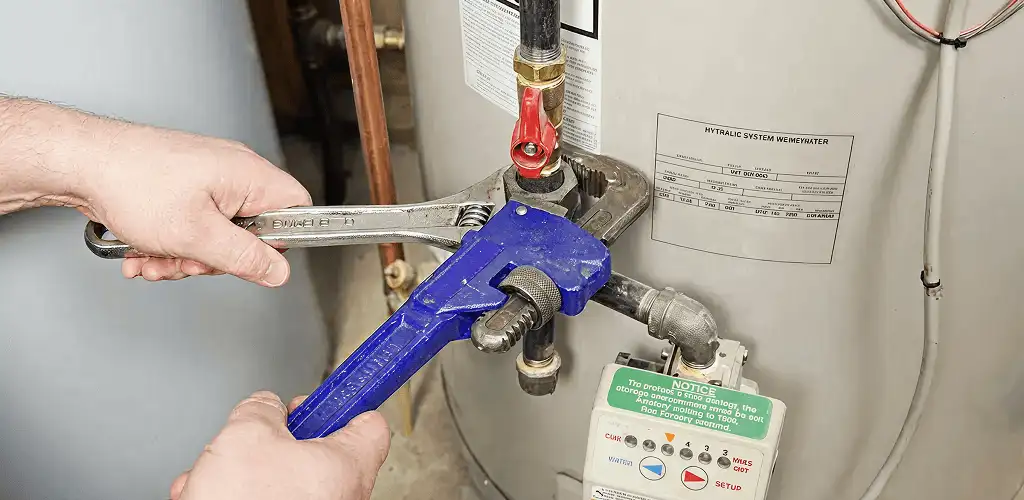 Water heater repair technician tightening the shutoff valve and supply line in Bakersfield, CA